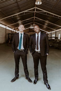 Two businessmen in suits smiling confidently while standing in an industrial hangar.